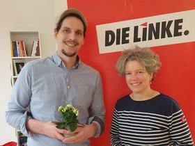 Thomas Iwan und Sabine Muhl stehen vor einem Aufsteller mit Schriftzug DIE LINKE